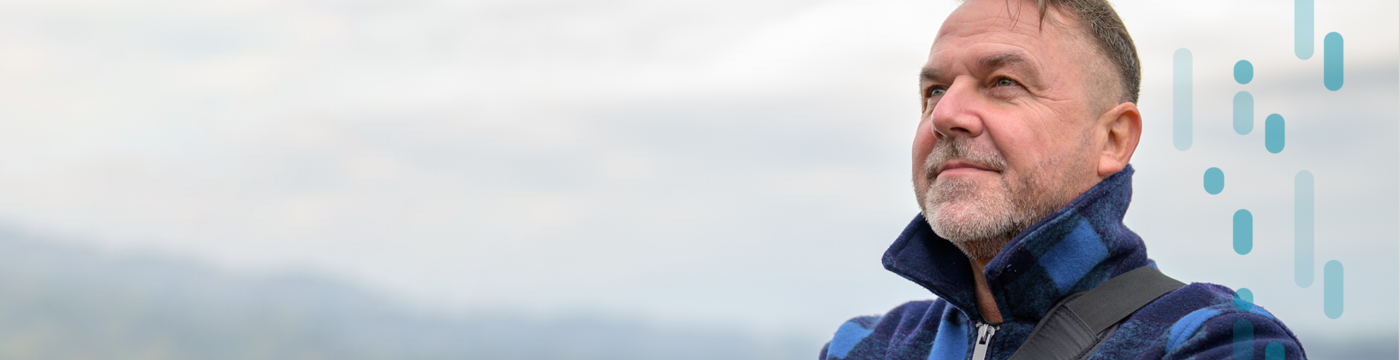 A man wearing outdoor gear looks confidently into the distance on an overcast day