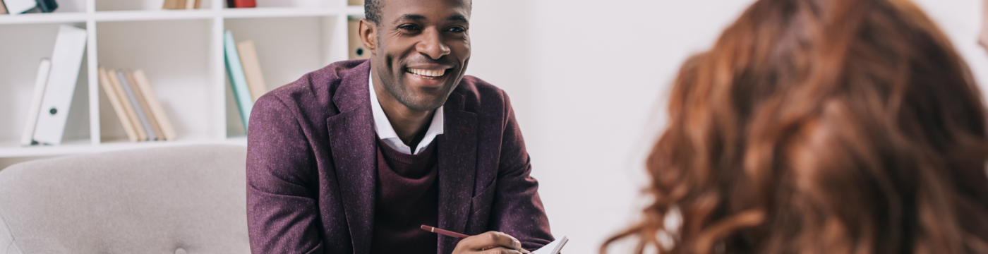 A professional therapist smiling and holding a pen speaking with a patient