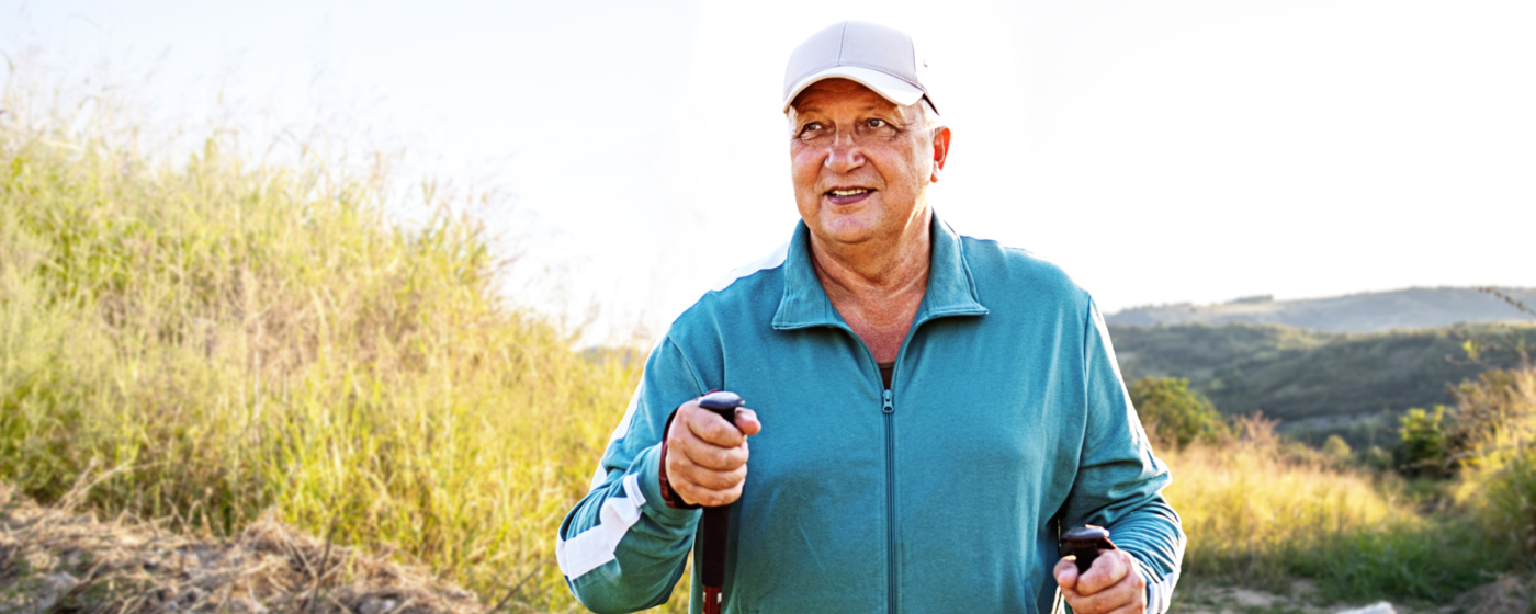 A man in a blue polo, hiking on a grassy hillside