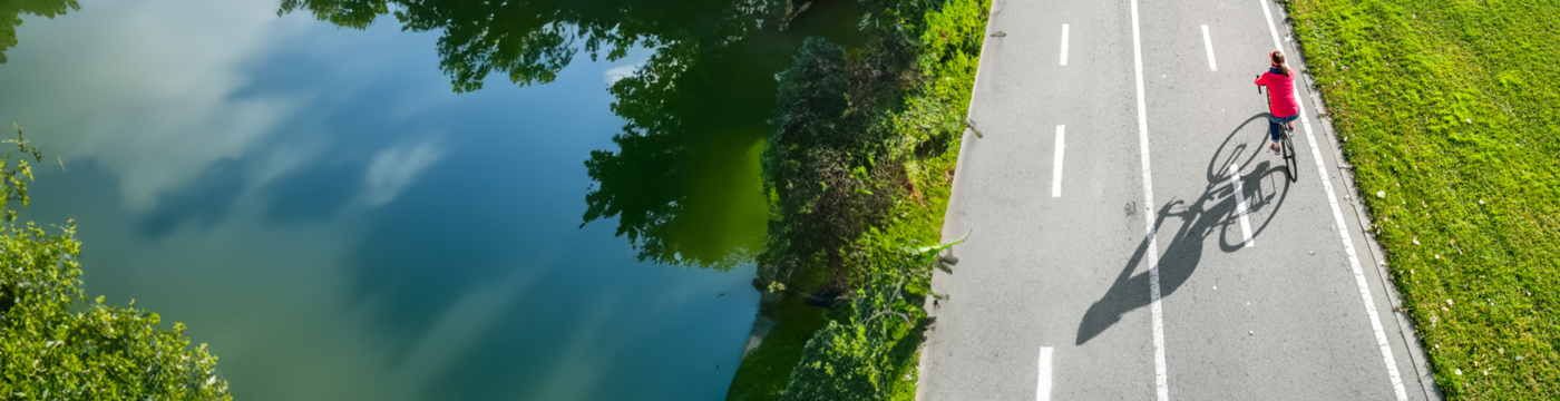 A man in a red jacket rides a bicycle along a bike path